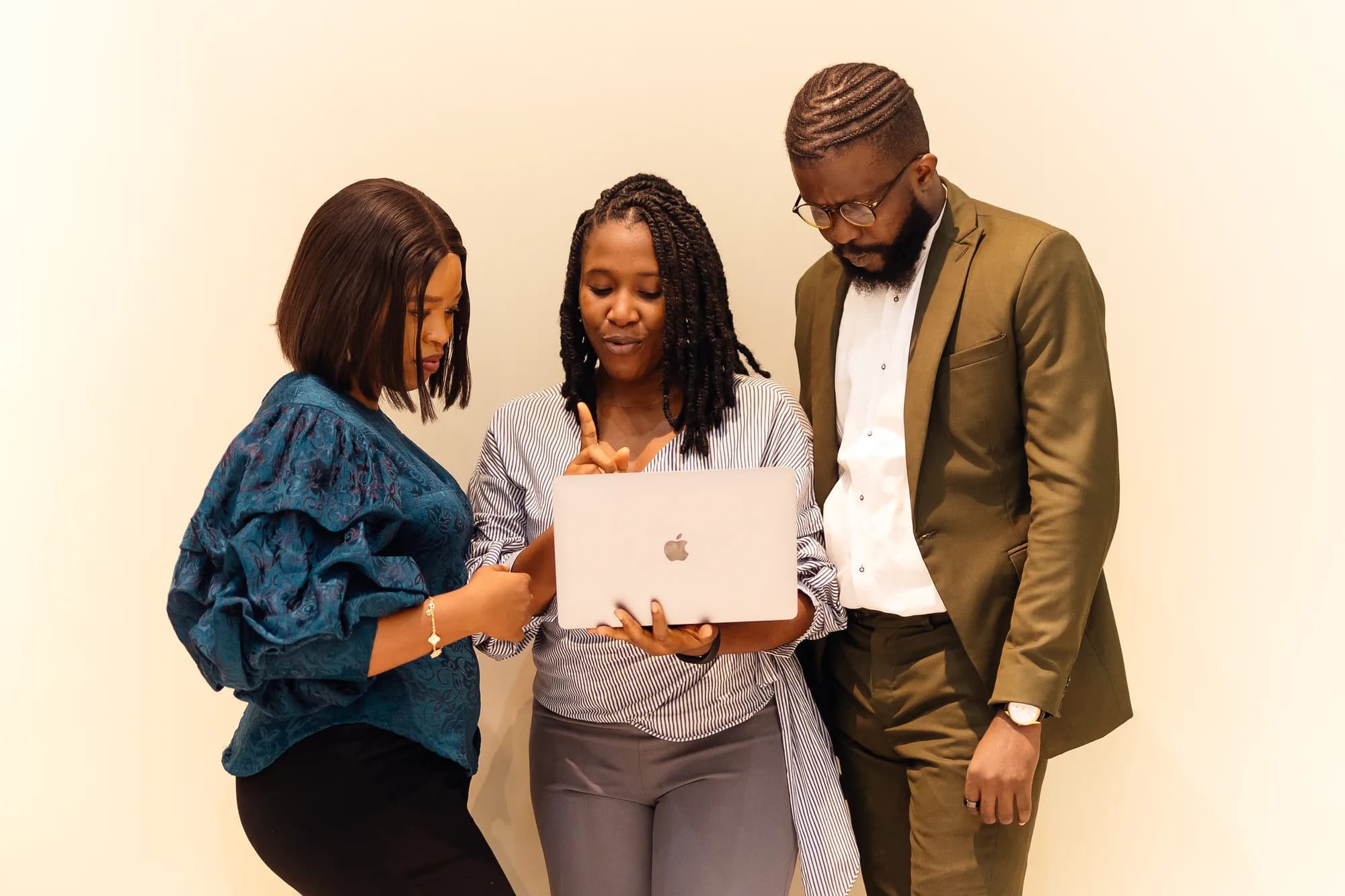 Three colleagues reviewing work together on a laptop